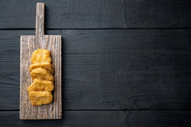 Pepite di pollo fritte sulla tavola di legno nera