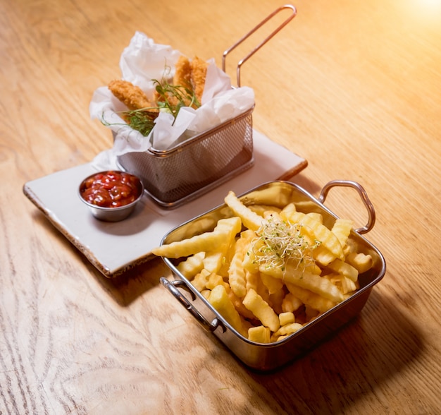 Pepite di pollo fritto con patatine fritte e salsa di pomodoro.