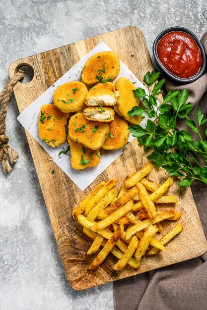 Pepite di pollo fritto fatte in casa con patatine fritte. Sfondo grigio. Vista dall'alto