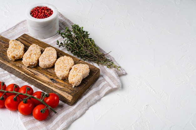 Pepite di pollo non cotte impostate su sfondo bianco tavolo in pietra con spazio per la copia del testo