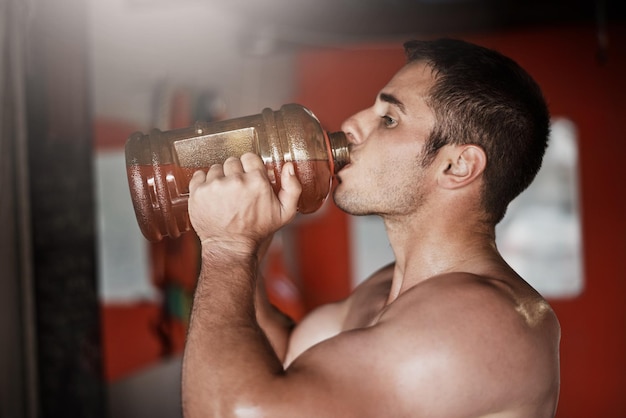 Per iniziare con un po' di pre-allenamento Ritagliata foto di un giovane bello e muscoloso che beve pre-allenamento in palestra