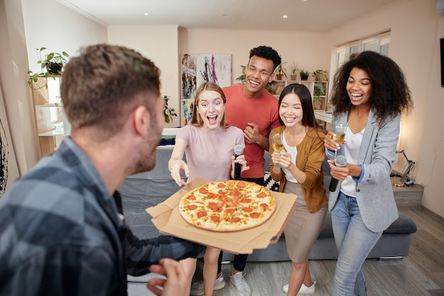 Per la tua festa, amici multiculturali eccitati hanno ordinato una pizza mentre cantavano con una festa di karaoke