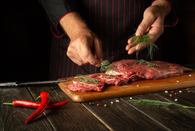 Per rendere gustoso il manzo è necessario aggiungere le spezie Lo chef mette le foglie di aneto sulla carne prima di grigliare