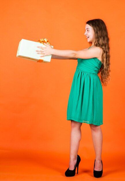 Per te bambino nel giorno d'estate su sfondo arancione il suo tempo di shopping piccola ragazza tenere scatola regalo ragazzino con confezione regalo festa di buon compleanno infanzia felicità festeggiamo le vacanze