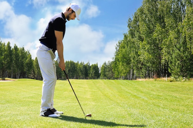 Per tutta la lunghezza del giocatore di golf che gioca a golf in una giornata di sole Giocatore di golf maschio professionista che prende colpo sul campo da golf