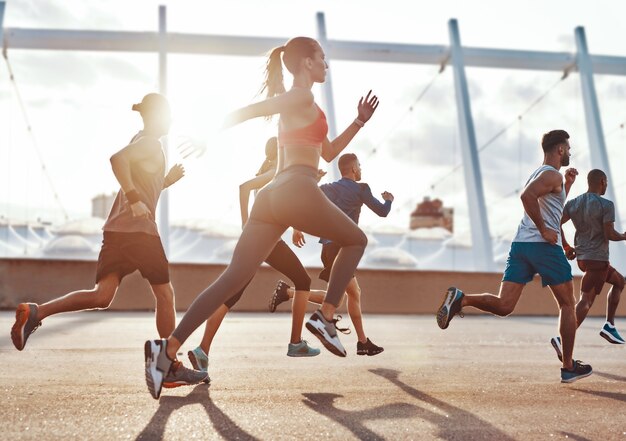 Per tutta la lunghezza delle persone in abbigliamento sportivo che fanno jogging mentre si allenano sul marciapiede all'aperto