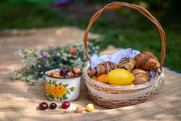 Per un pic-nic preparate croissant ciliegie frutta limone arancia e un bouquet di fiori di campo