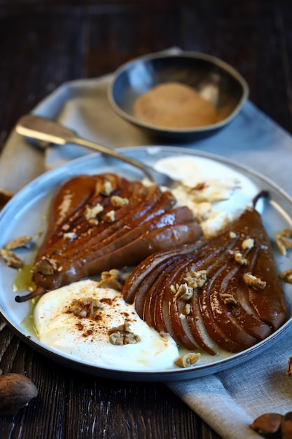 Pera caramellata con noci e crema al burro su un piatto Dessert sano