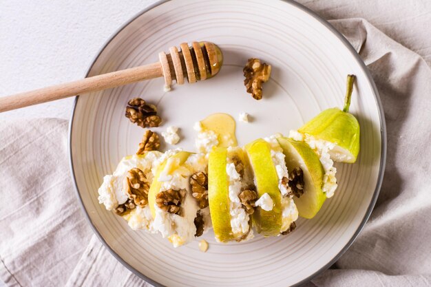 Pera con miele di ricotta e noci a strati su un piatto Cibo sano Vista dall'alto Primo piano