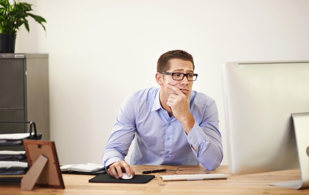 Perché l'ho lasciato per la fine della giornata Foto di un uomo d'affari che sembra incerto mentre lavora al suo computer