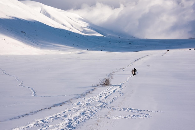 Percorso delle impronte del paesaggio invernale e persone che camminano nella valle della neve in una luminosa giornata di sole