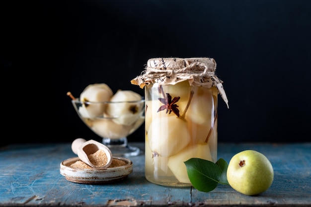 Pere con spezie sciroppate in un barattolo su sfondo scuro Delizioso dessert per le vacanze