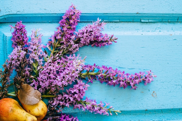 Pere fresche e fiori viola Dactylorhíza su un vecchio fondo di legno blu