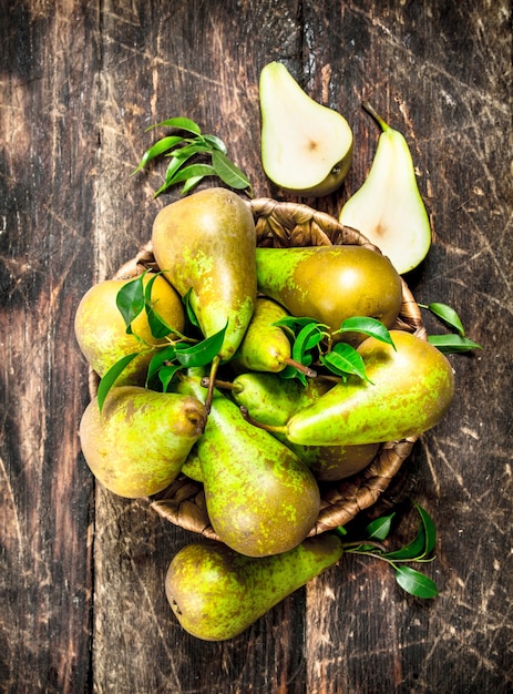 Pere fresche in un canestro. Su uno sfondo di legno.