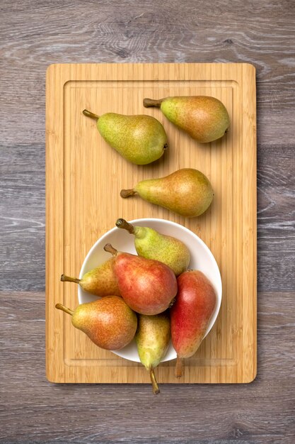 Pere succose mature in una ciotola su un fondo di legno