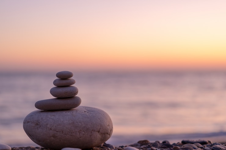 Foto perfetto equilibrio di pila di ciottoli in riva al mare verso il tramonto