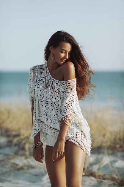 Perfetto giovane donna boho in piedi su una spiaggia tropicale di sabbia contro il bellissimo spazio copia bokeh