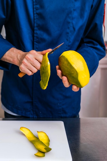 Perfezione del mango Primo piano delle mani di un pasticcere che sbucciano sapientemente un mango maturo con un coltello