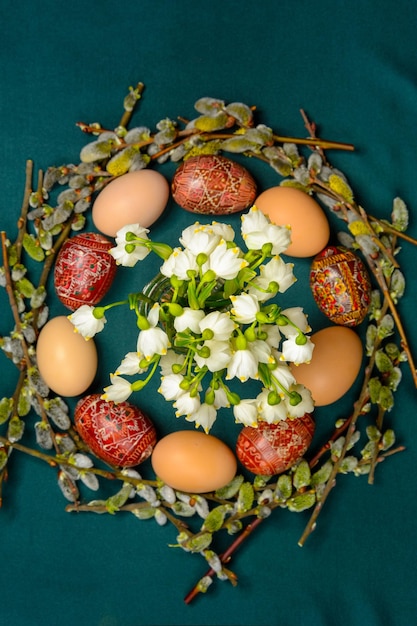 Perla primaverile di peso intorno alle uova di Pasqua e ai rami di salice su uno sfondo scuro