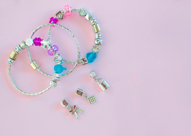 Perline multicolori per fare gioielli su sfondo rosa Bellissimo braccialetto con perline di plastica in metallo il concetto di gioielli fatti in casa