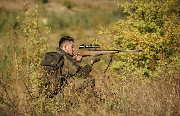 Permesso di caccia Attrezzatura da caccia per professionisti La caccia è un hobby maschile brutale Il cacciatore serio barbuto trascorre la caccia per il tempo libero Il cacciatore tiene il fucile L'uomo indossa abiti mimetici sullo sfondo della natura