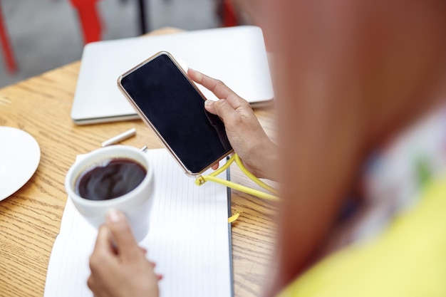 Persona che guarda lo smartphone mentre alza la tazza di caffè