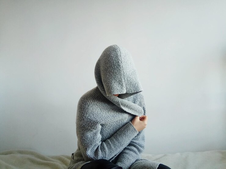 Foto persona che indossa abiti caldi seduta sul letto contro la parete