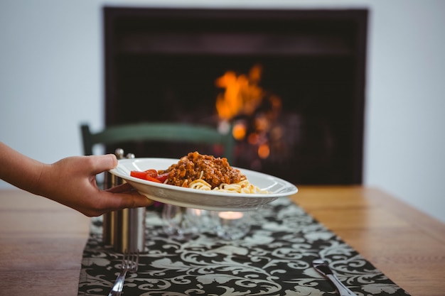 Persona che mette gli spaghetti sul tavolo a casa