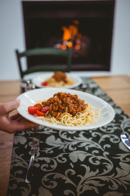 Persona che mette gli spaghetti sul tavolo a casa