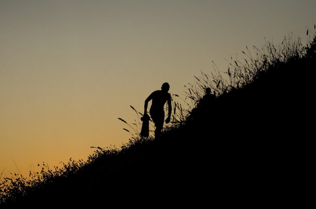 Persona che scala una montagna per guardare il tramonto