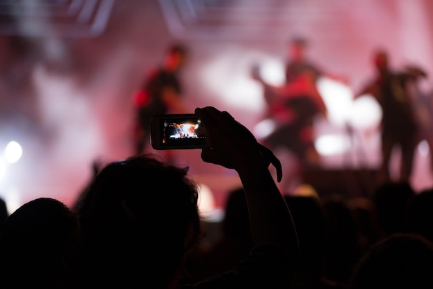 Persona che scatta foto con il telefono cellulare durante un concerto