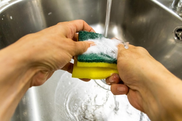 persona che si lava le mani con il sapone nel lavello della cucina