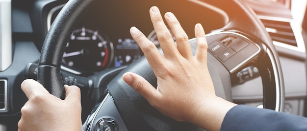 Persona che spinge il clacson durante la guida seduta su un'auto per premere il volante, suonando il clacson per avvertire le altre persone nel concetto di traffico.