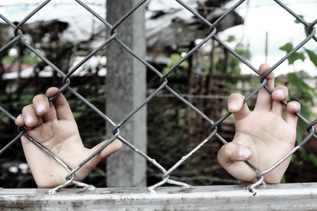 Persona che tiene il bastone vista attraverso la recinzione a catena