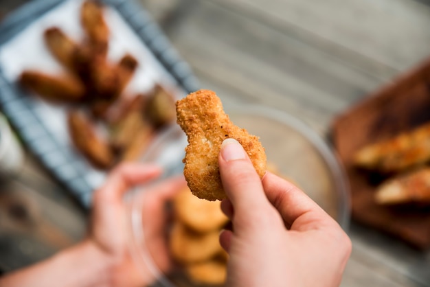 Persona che tiene la pepita di pollo dorata croccante