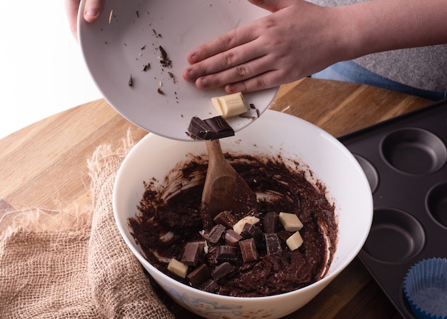 Persona che tiene la zolla con cioccolato che prepara pasta per muffin