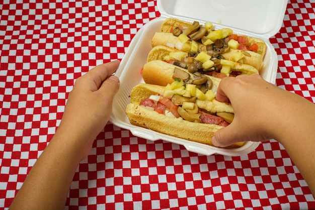 Persona che tiene un hot dog Hot dog con ananas e funghi.