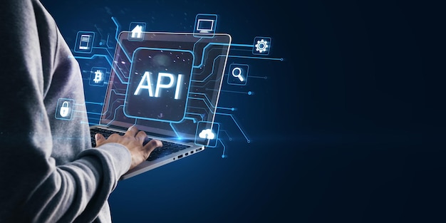 Persona che utilizza un portatile con icone API illuminate e simboli di rete in blu su uno sfondo scuro
