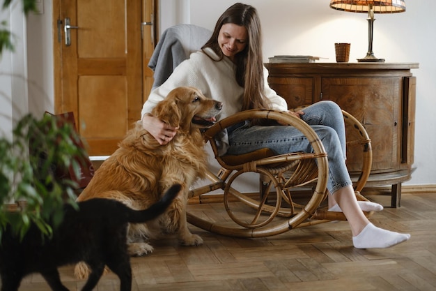 Persona con cane golden retriever sulla sedia a dondolo a casa