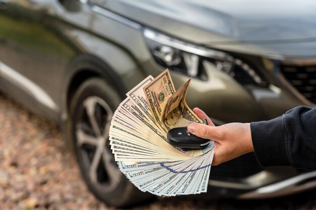 Persona con denaro e chiave dell'auto in piedi davanti all'auto Concetto di prestito assicurativo Affare di acquisto o noleggio di una nuova auto
