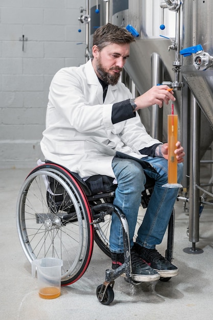 Persona con disabilità che usa una sedia a rotelle che lavora in una fabbrica di birra artigianale