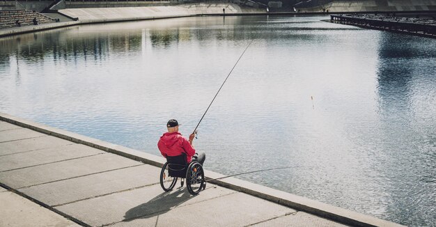 Persona con disabilità fisica che utilizza la sedia a rotelle per pescare dal molo di pesca