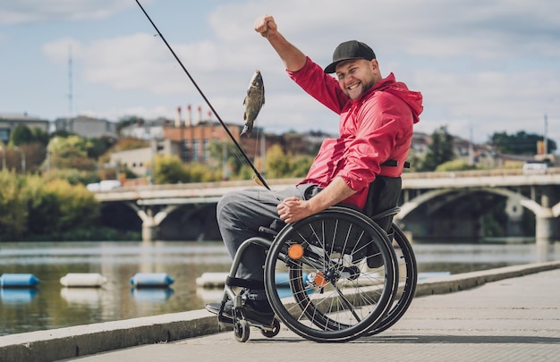 Persona con disabilità fisica che utilizza la sedia a rotelle per pescare dal molo di pesca