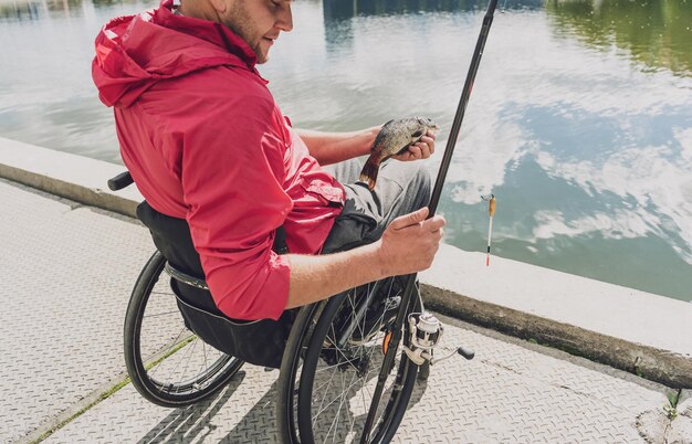 Persona con disabilità fisica in sedia a rotelle che pesca dal molo di pesca