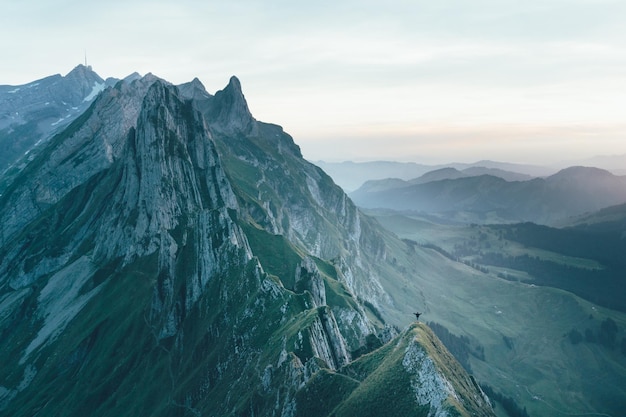 Persona con le braccia tese sulla vetta della montagna