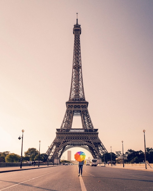 Persona con un ombrello colorato in piedi contro la Torre Eiffel in città contro il cielo