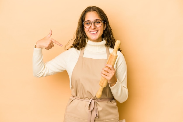 Persona di donna giovane chef caucasico che punta a mano uno spazio di copia camicia, orgoglioso e fiducioso