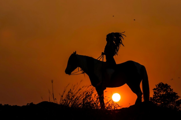 Persona di sagoma a cavallo al tramonto
