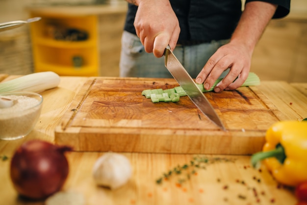 Persona di sesso maschile che cucina carne con verdure in padella