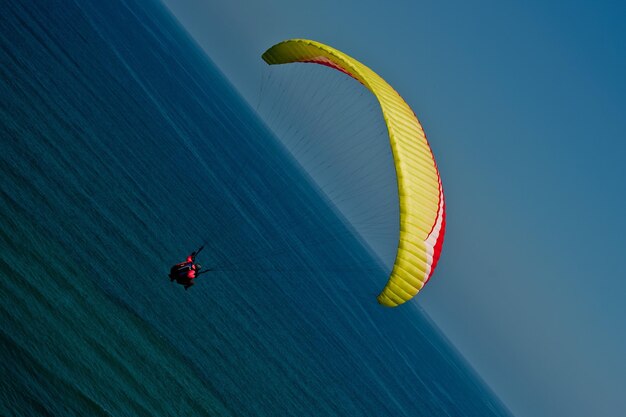 Persona in parapendio sul mare contro un cielo blu limpido